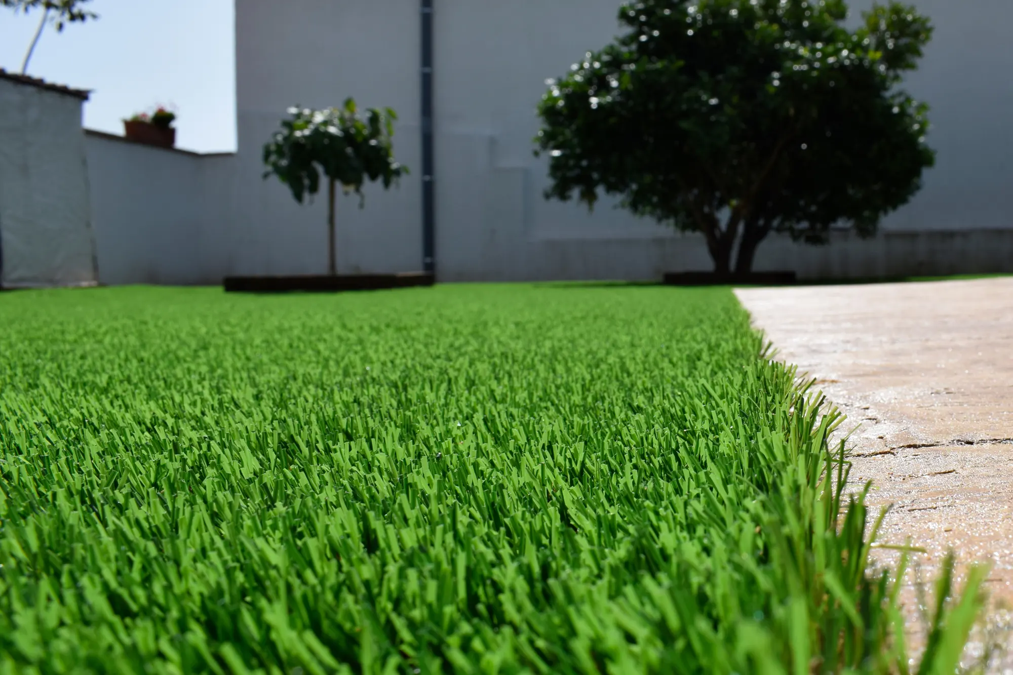 Instalación de césped artificial en jardín particular con acabado decorativo en madera.