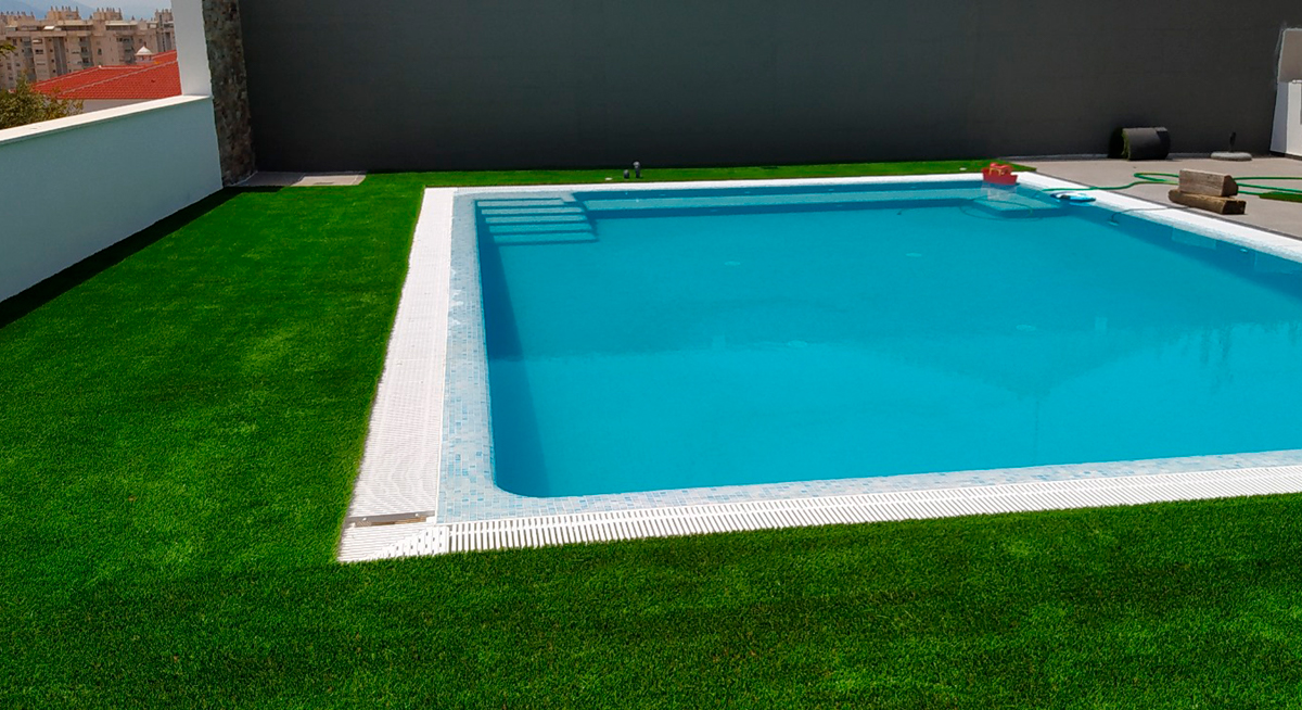Zona de piscina con césped artificial antideslizante y drenaje.