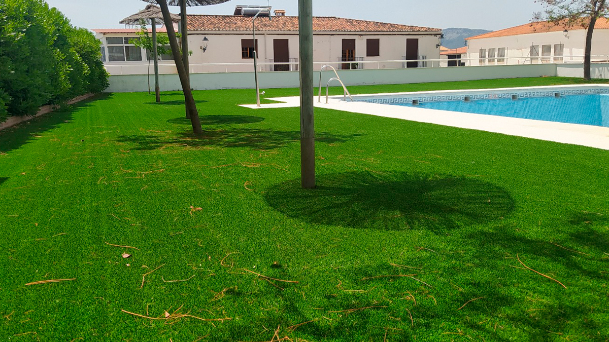 Instalación profesional de césped artificial en zona residencial con piscina.